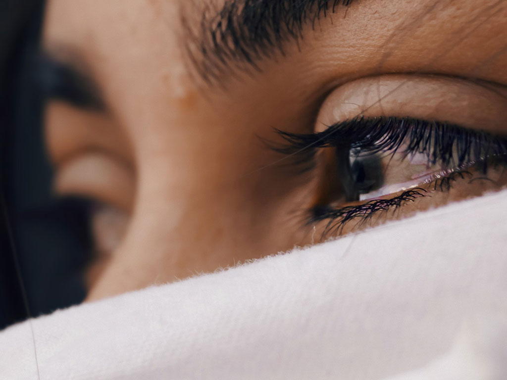 Woman with face covering teary eyed